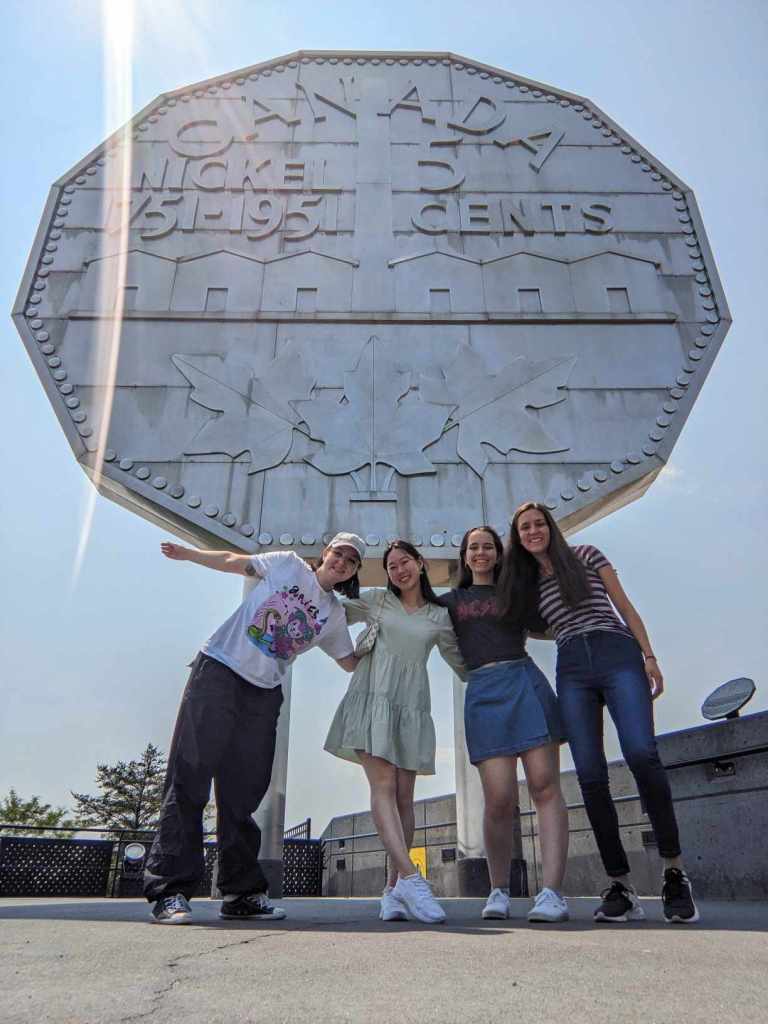 A group of young adults (Science Communication interns) standing outside the Big Nickel monument in Sudbury, Ontario.
