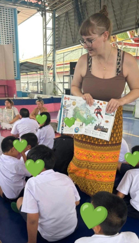 Me standing in a classroom in Thailand, teaching students about Canada.