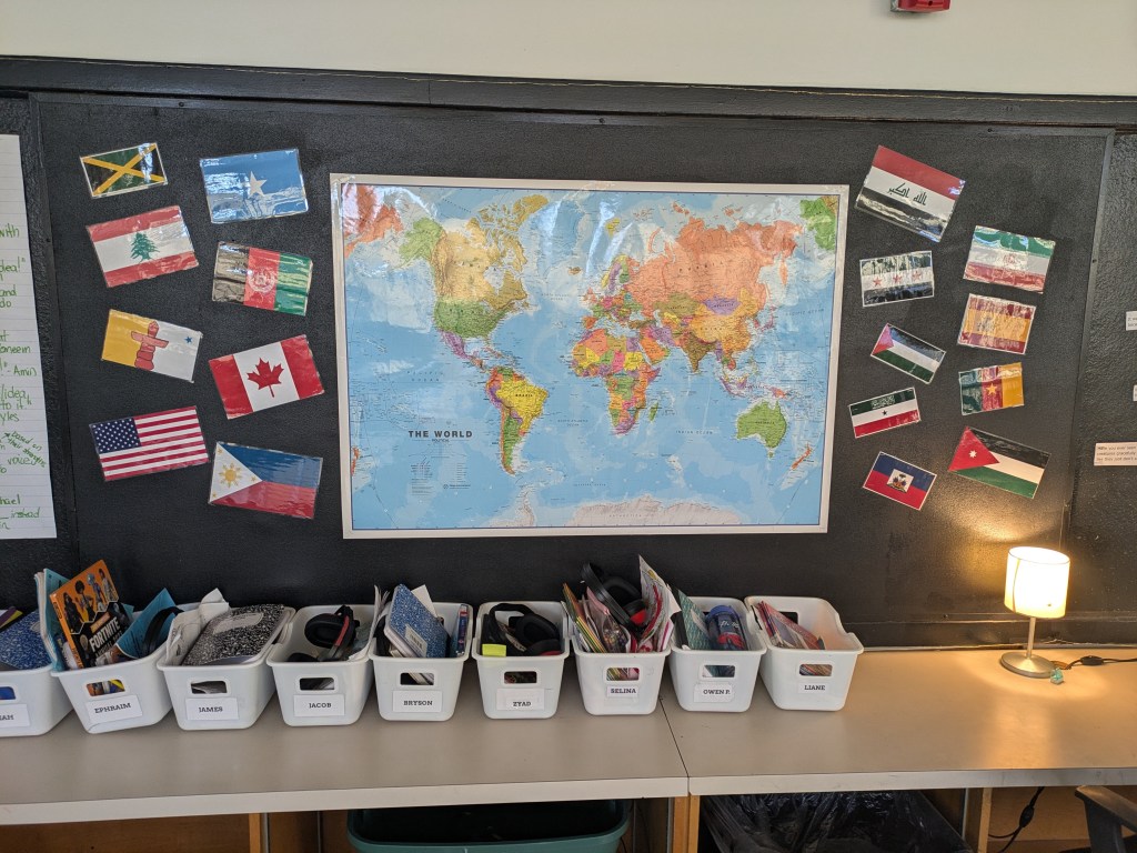 A classroom wall displaying a world map connected to strings of flags representing students' countries of origin.